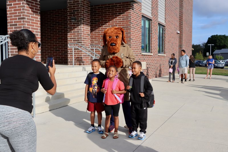 Falan Mifflin, left, gets a photo of her students, Alijah Hylton, Mimi Davis and Aidan Hylton, with McGruff the Crime Dog. The popular police mascot was there wish kids a safe and healthy school year. BILL SHULL PHOTO